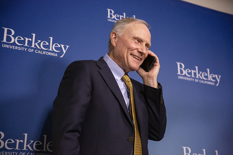 David Card speaks to someone on his cell phone at a campus broadcast studio where he participated in a news conference about his Nobel Prize win.