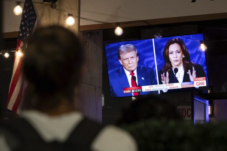 a person stops to watch a screen displaying the US Presidential debate between Vice President and Democratic presidential candidate Kamala Harris and former US president and Republican presidential candidate Donald Trump.