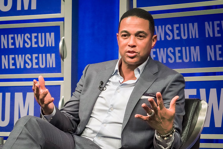 CNN anchor Don Lemon seated and speaking causally against a backdrop banner of the Newseum in Washington, D.C.