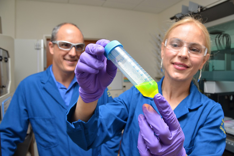 Julia Schaletzky with a vial of yellow fluid, with Eddie Wehri in the background