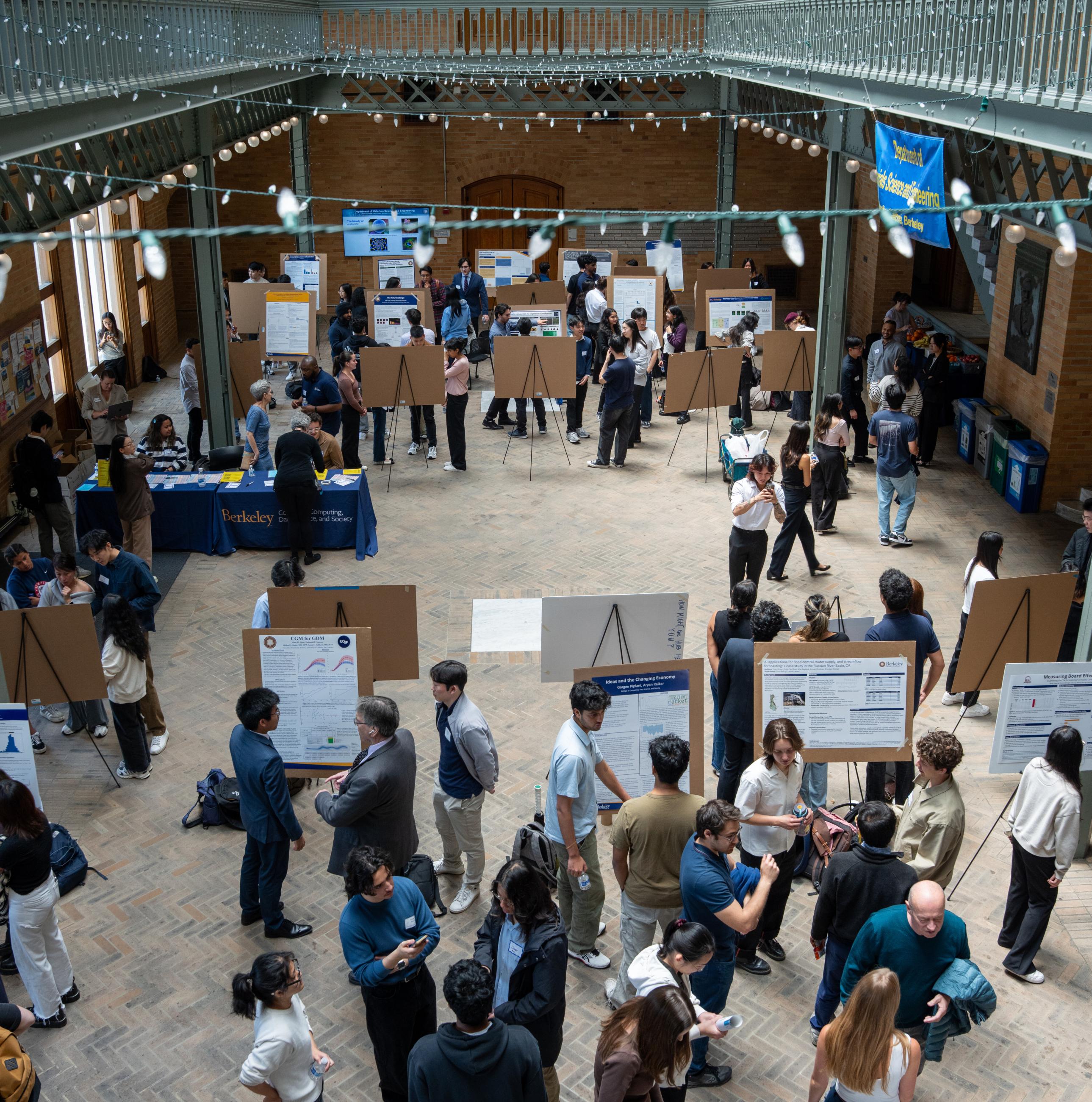 Students discussing research at a large poster session inside an atrium