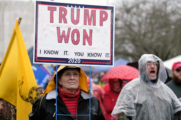Woman holds protest sign proclaiming Donald Trump's 2020 victory, months after he lost the electionsigning