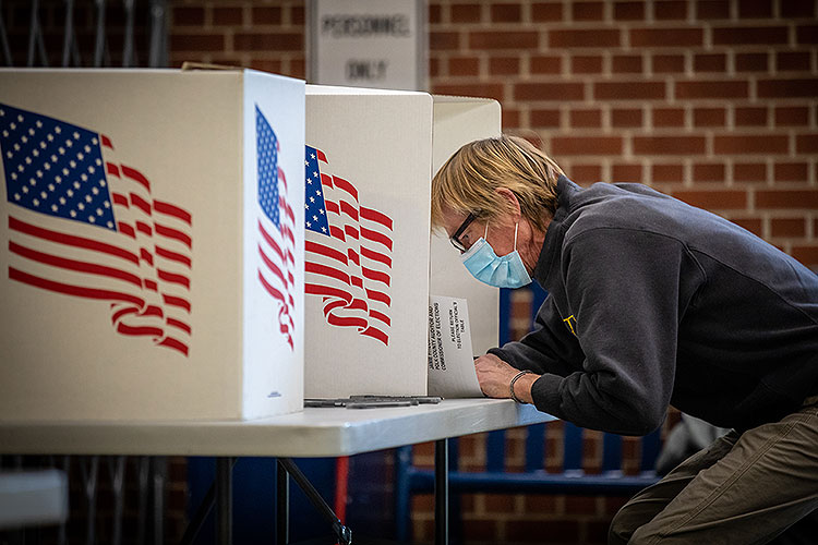 voter at ballot box wearing a surgical mask against COVID-19 virus