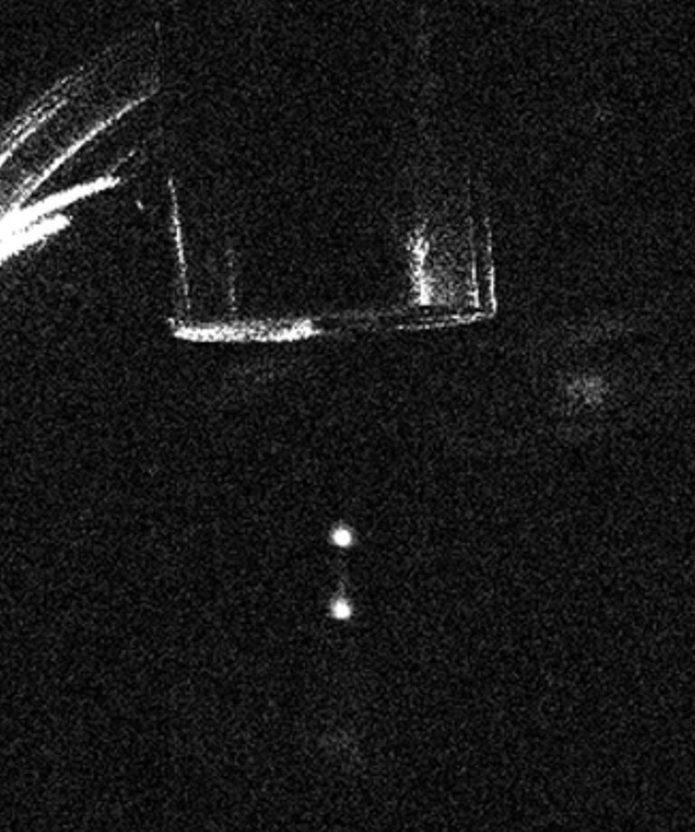 against a black background, two white glowing balls sit below a faint tungsten disk in the lattice atom interferometer