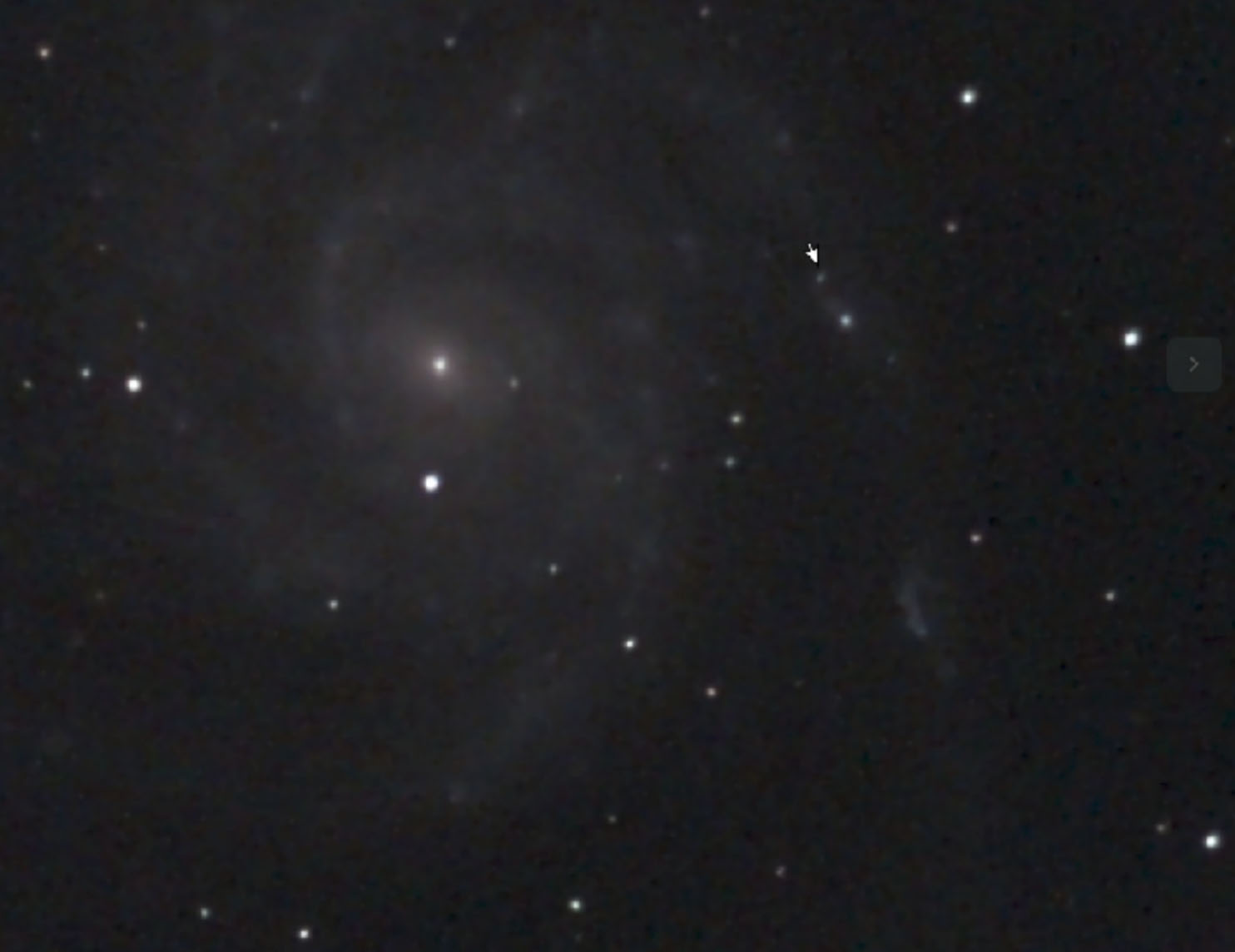 photo of a pinwheel shaped galaxy, white spiral against a dark background