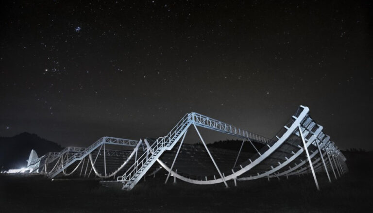 looping steel structure lit up against a starry sky