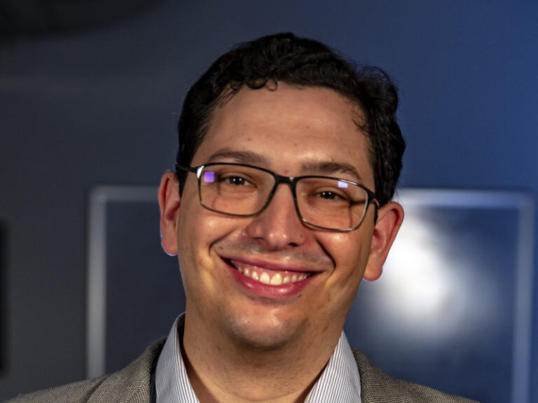 headshot of man with glasses smiling