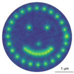 Smiley face made up of green dots against a dark blue circle created using an electron beam.