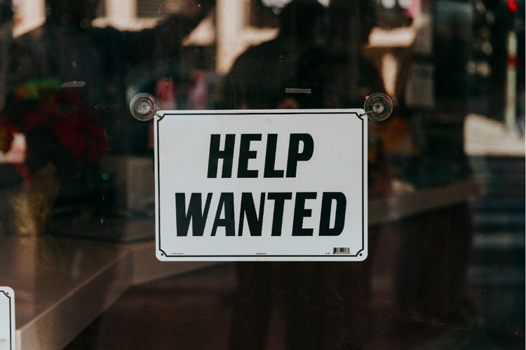 a Help Wanted sign on a glass door