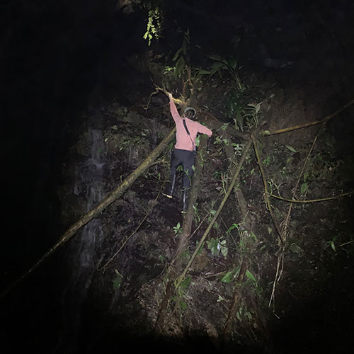 A low-quality night time photo shows Brunner balancing on a the side of a rock face.
