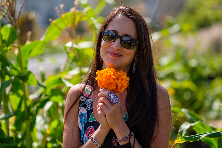 Associate professor Elizabeth Hoover holds marigolds and smiles in the Indigenous Community Learning Garden.