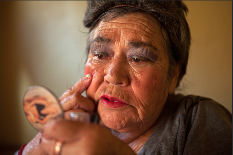 An elderly sex worker puts makeup on