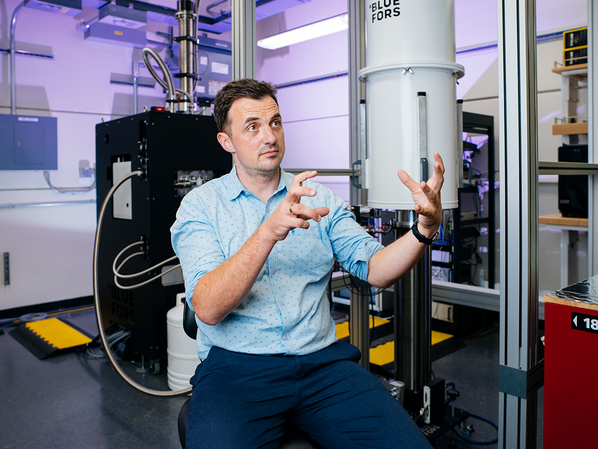 James Analytis in lab hands held in front of body as he explains superconductivity.