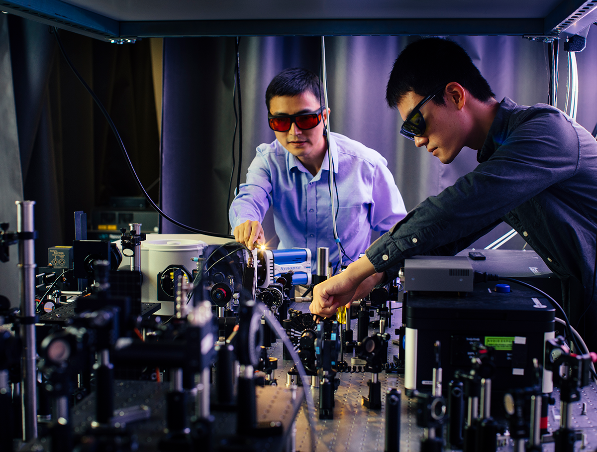 Jie Yao and Fanhao Meng in Yao Lab wearing protective eyewear while adjusting lasers in the lab.