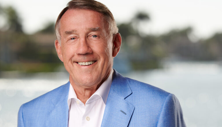 a man in a blue jacket and white shirt smiling at the camera