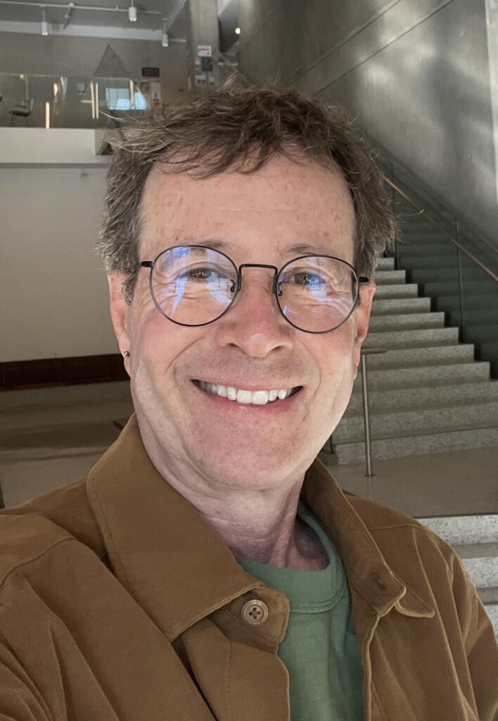 headshot of man smiling in glasses 