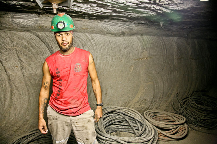 A Mexican miner in a red t-shirt at an underground work site