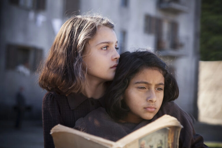 Two young girls sit closely together in this scene from the HBO series 