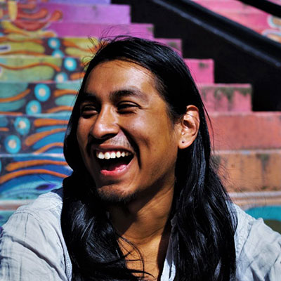 Jesus Nazario, a Ph.D. student in ethnic studies smiling in front of a colorful stairway.