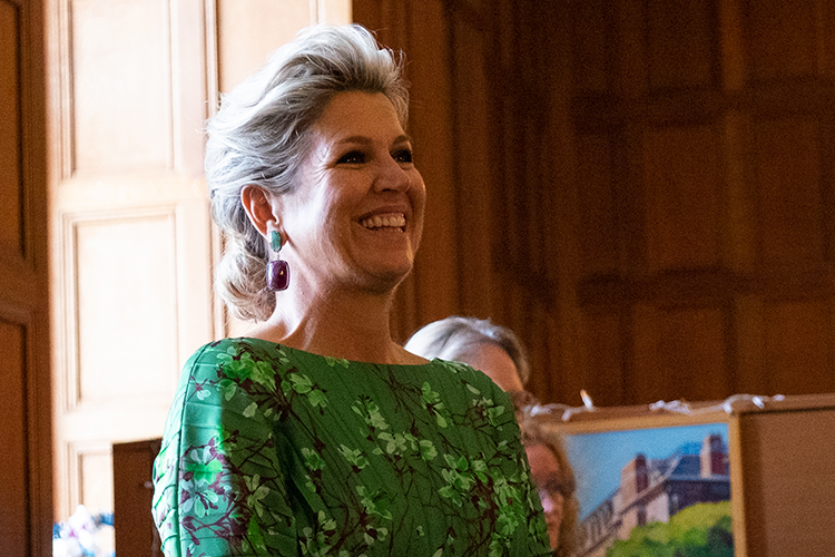Queen Maxima of the Netherlands smiles and laughs in the Morrison Library at an event.