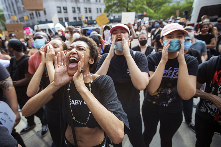 Female protesters chant with their hands at raised at their mouths