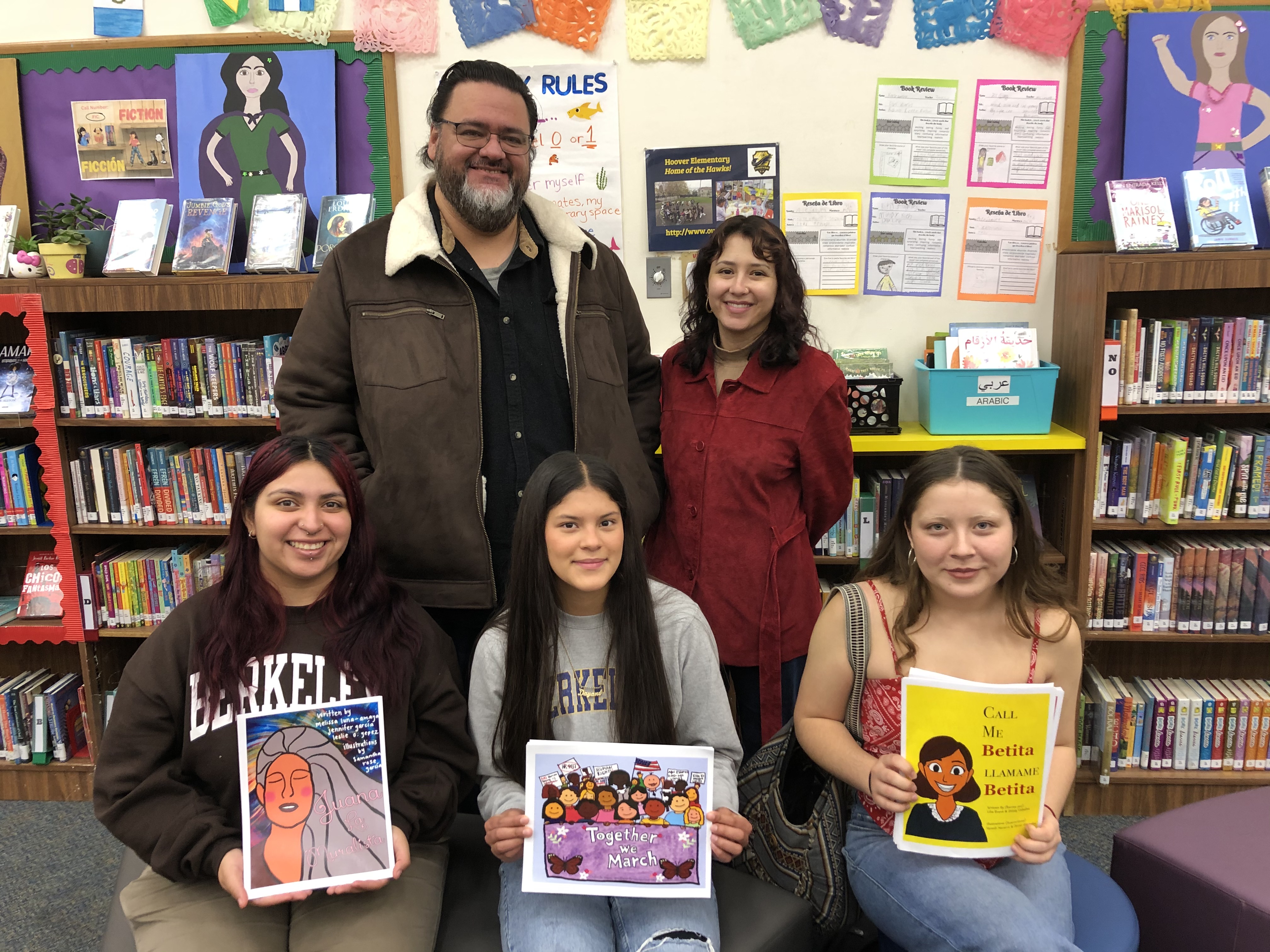 Berkeley students Jennifer Garcia, Dayane Silva and Lilia Evans (front) hold up the children's books they read to Hoover Elementary School students. The school's librarian, Kristen Flores and Pablo Gonzalez stand behind them.