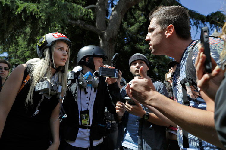 Protesters, some in helmets, some not, yell at each other during an outdoor protest