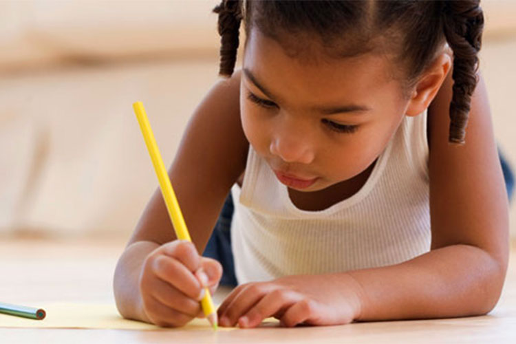 Image of pre-K child on floor writing