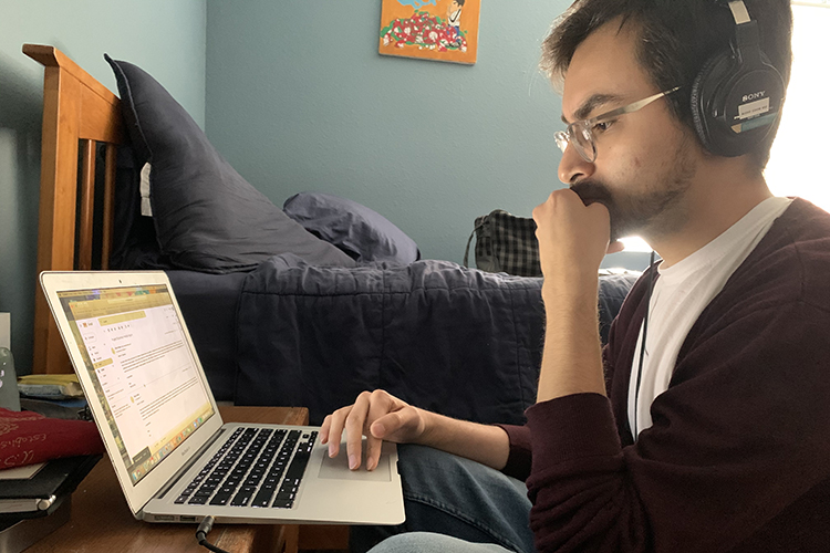 Ricky Rodas sits at his desk working on his laptop