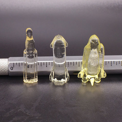 A photo shows three translucent rockets lined up in front of a ruler for scale.