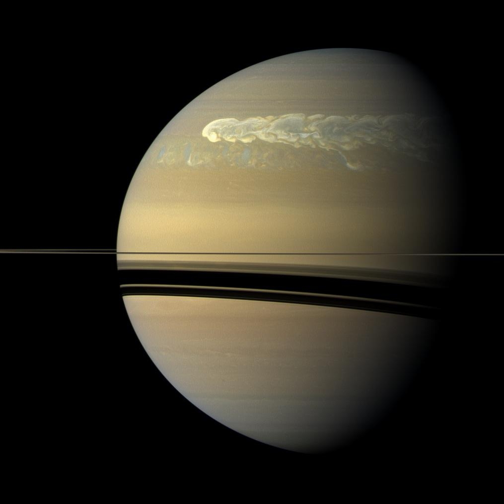 closeup of beige planet with stormy swirls at top and shadow of rings at middle