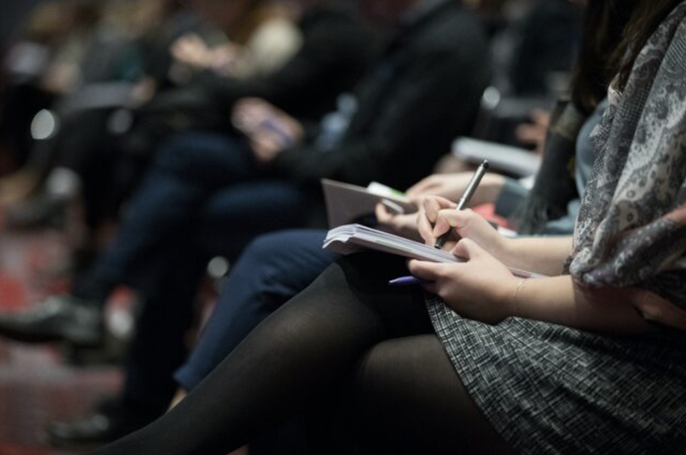 image of someone holding a notebook in their lap and writing in it