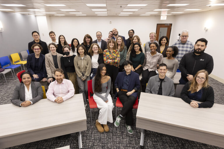 an image of various people in business casual clothes smiling at the camera in a conference room