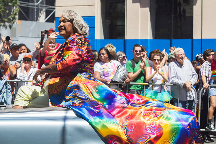 Miss Major on a car float wearing a colorful dress.