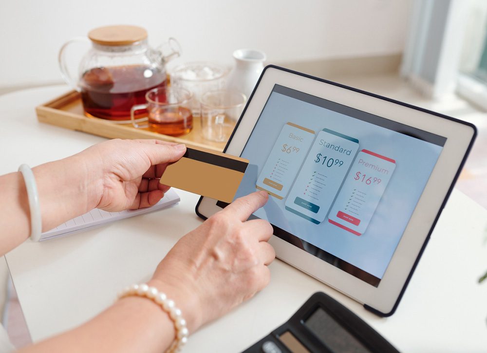 Hands of senior woman choosing subscription or payment plan on tablet computer and paying with credit card