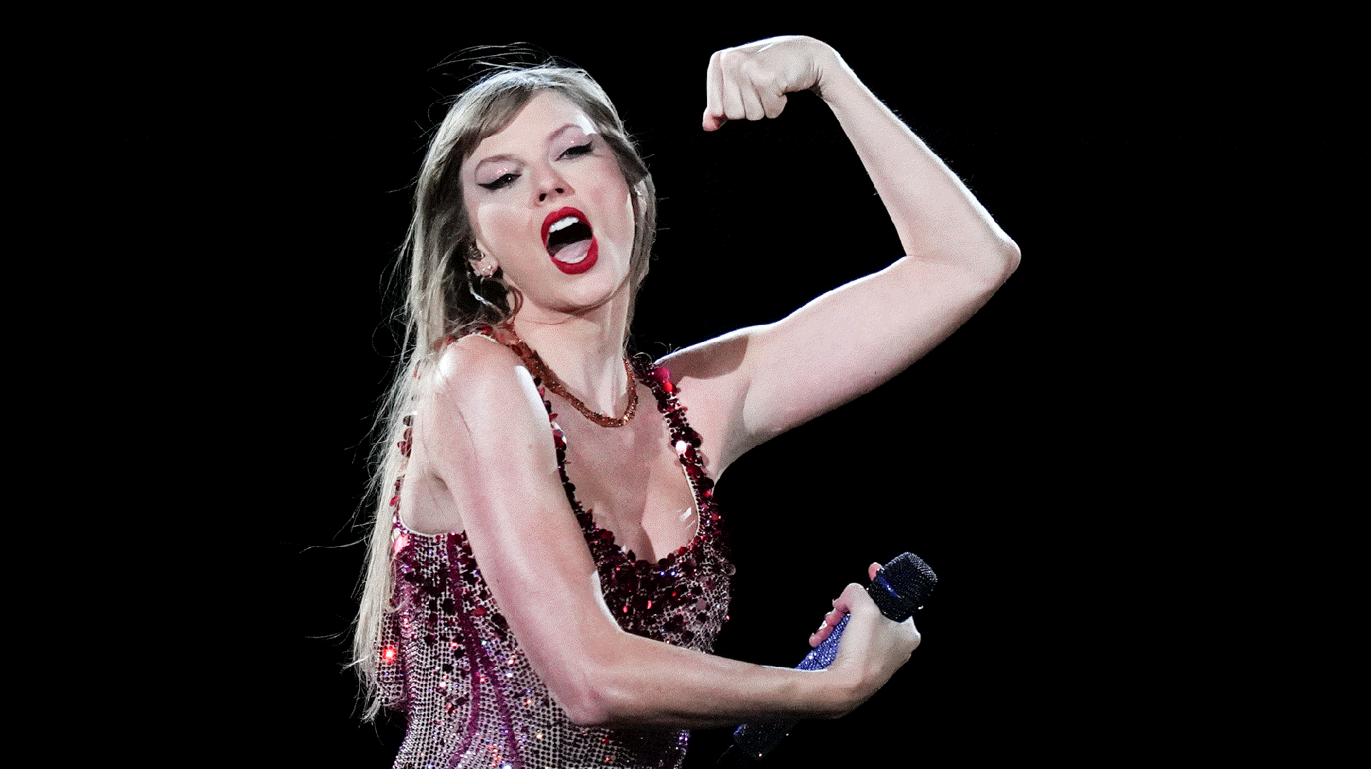 During a dynamic performance, Taylor Swift flexes muscles in her left arm as she sings