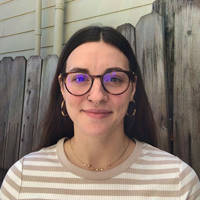 Tessa Scott, a Ph.D. student in linguistics standing in front of a fence