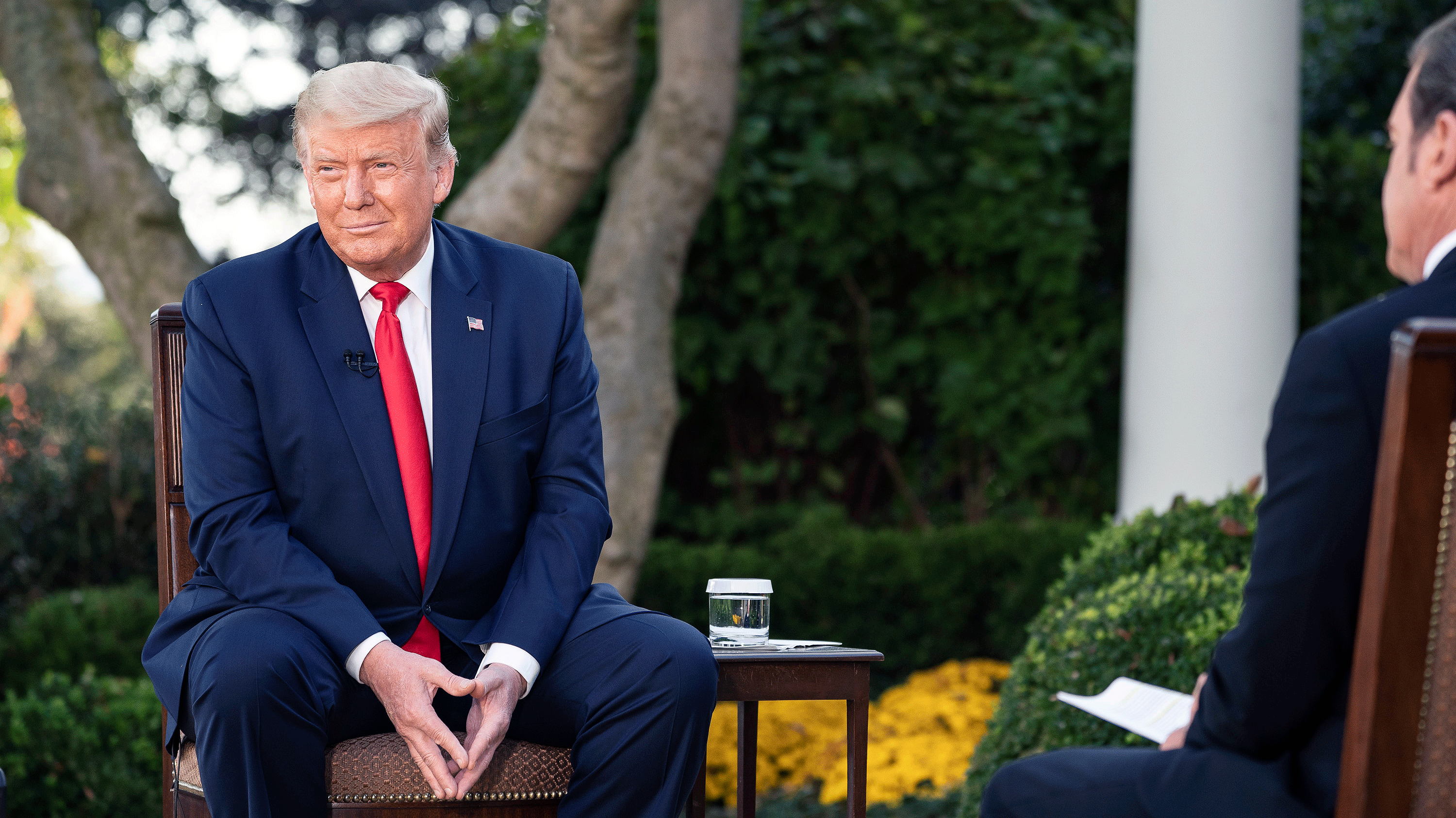 Donald Trump, wearing a blue suit, white shirt and red tie, sits pensively in the White House Rose Garden during an October 2020 town hall event sponsored by conservative Sinclair Broadcast Group 
