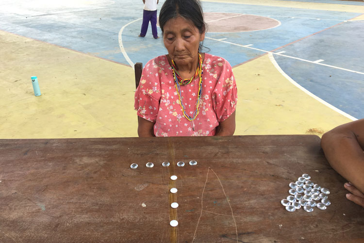 A Tsimane' woman tallies glass beads and white buttons.