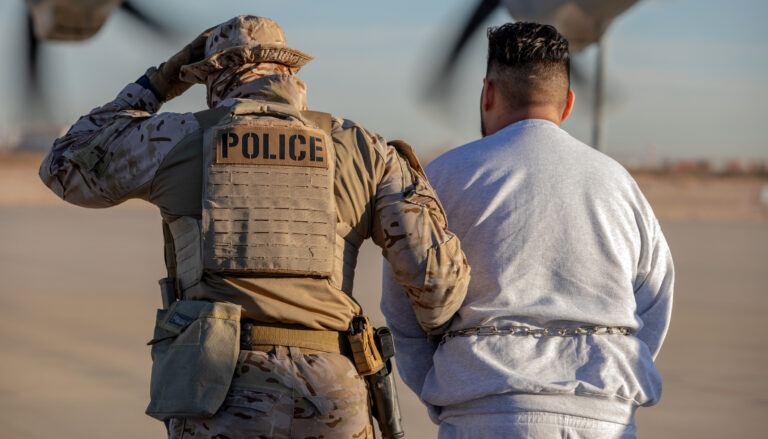 A photo showing from behind a person in military fatigues and a sidearm in a holster, with a