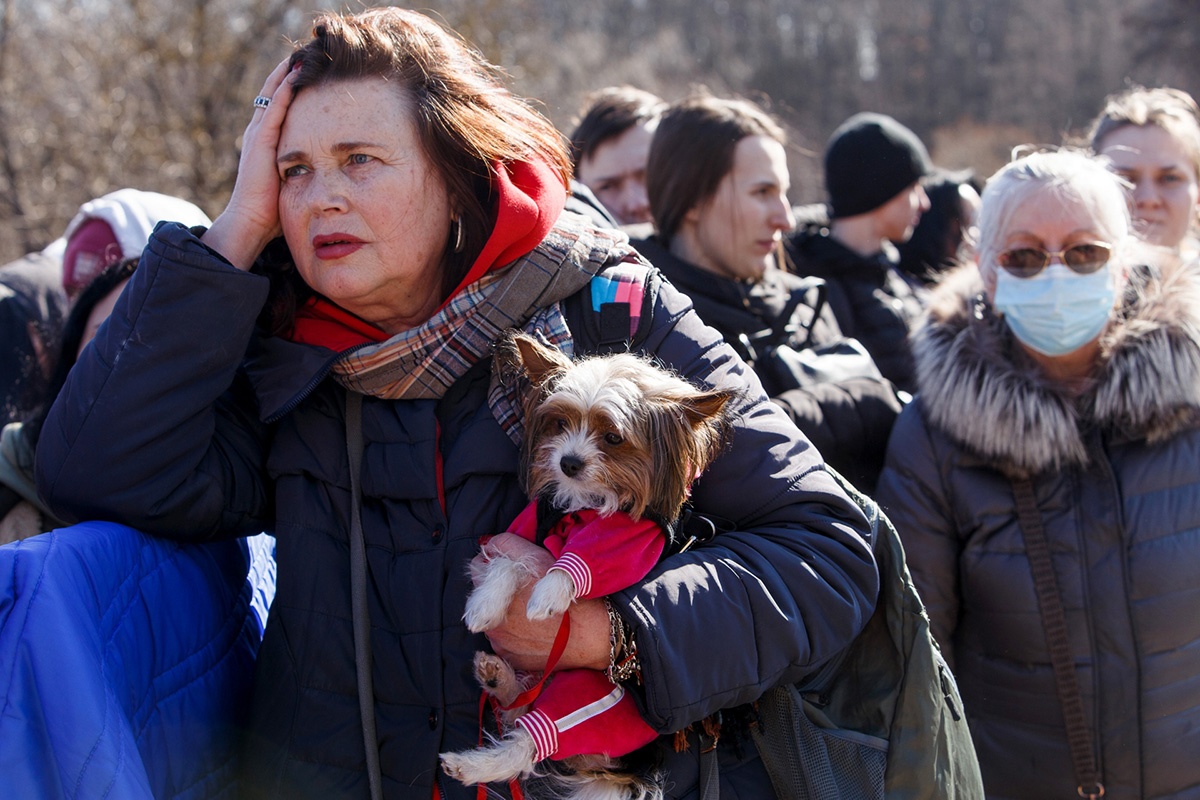 A Ukrainian woman, carrying a small dog in her arms, waits at a border crossing to escape the war in her home country 