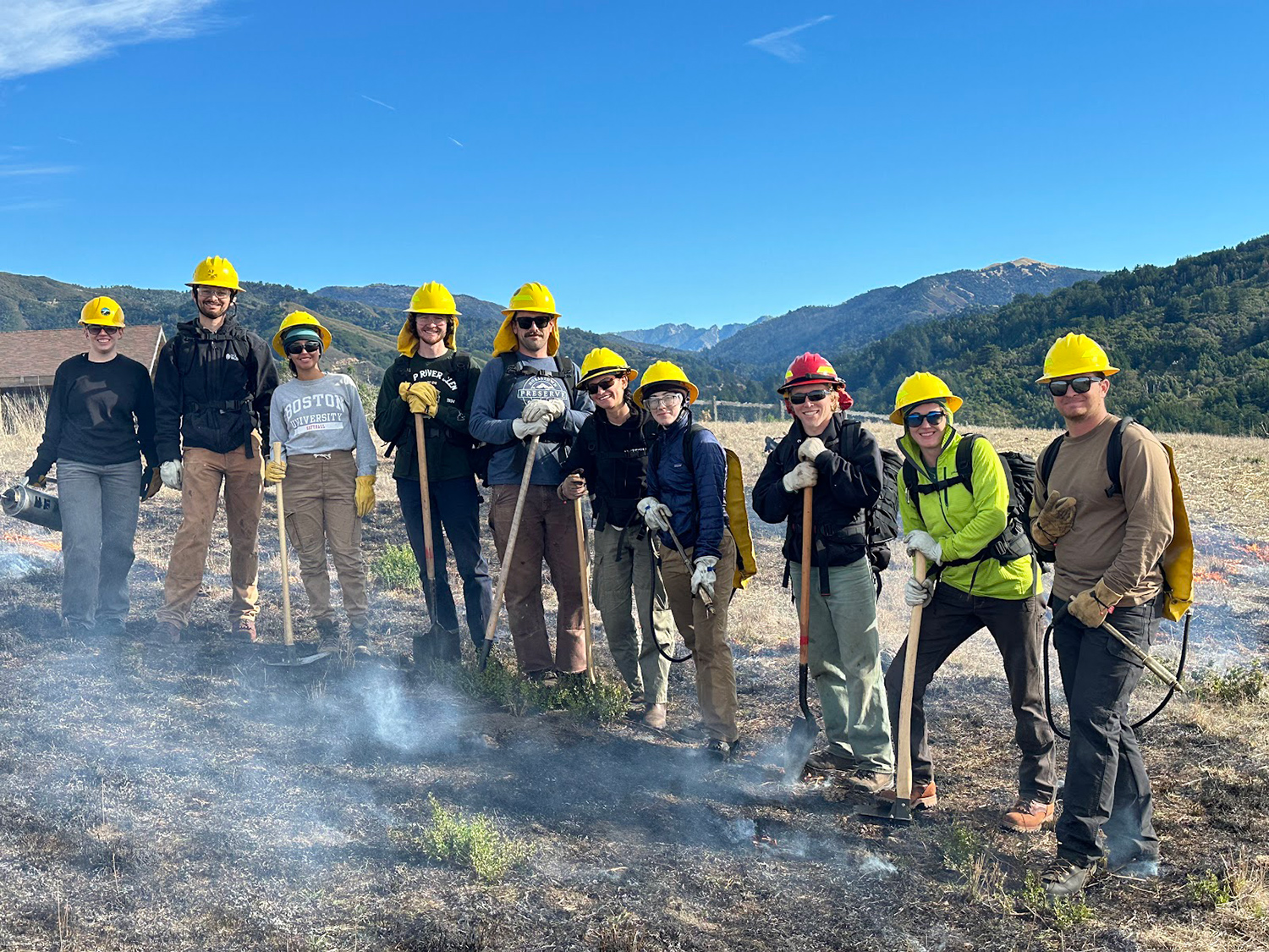 Americorps workers in hardhats posing outdoors