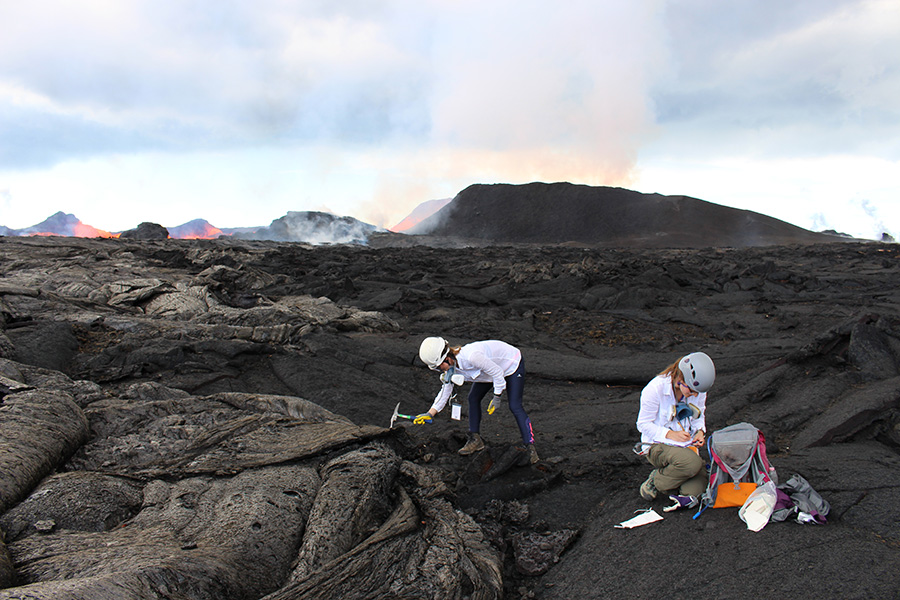 Two scientist capturing and documenting findings on a volcano.