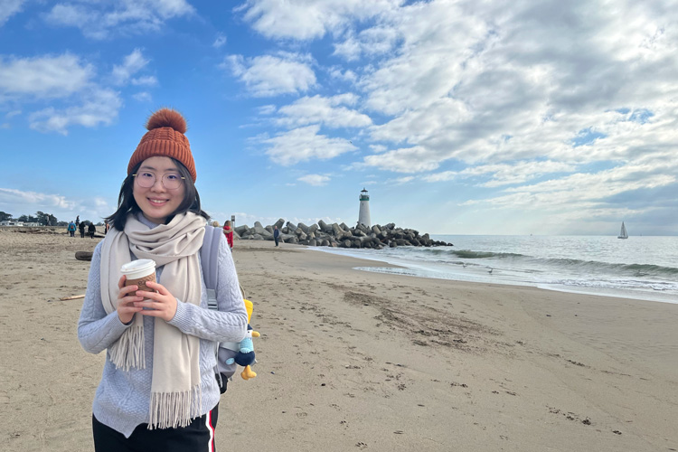 Xinyi Liu on the beach with lighthouse in background