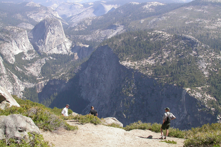 three people on rocks with Half Dome in the background