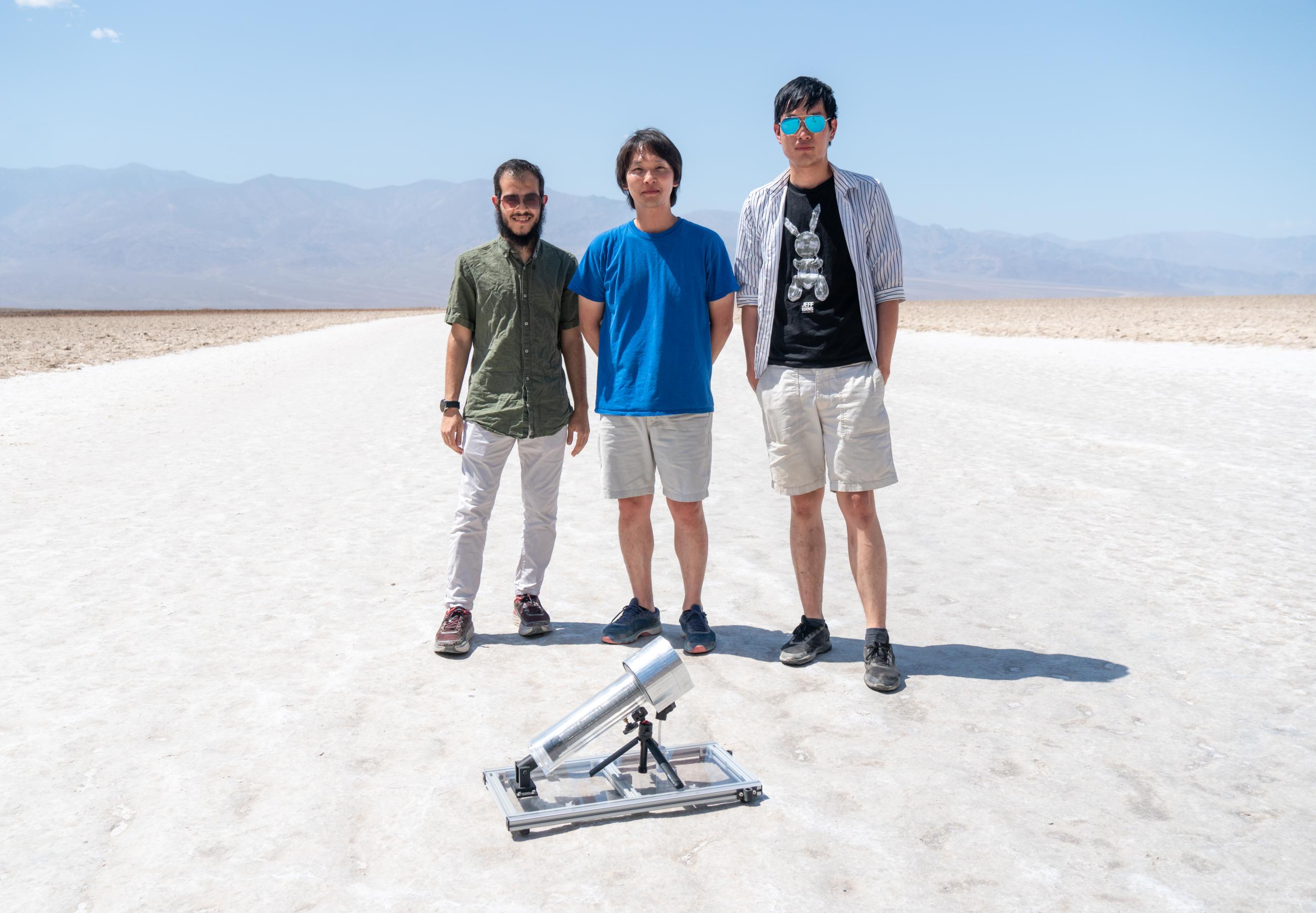 Three scientists standing in front of a MOF in the desert
