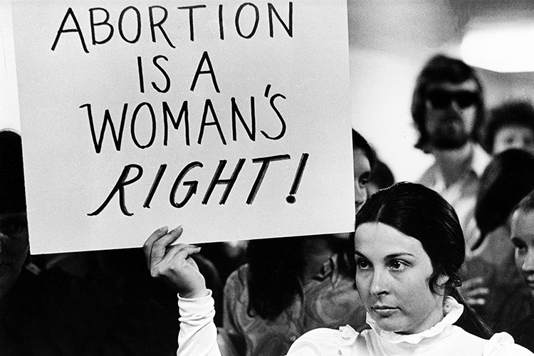 a person holds up a sign that reads "Abortion is a woman's right."