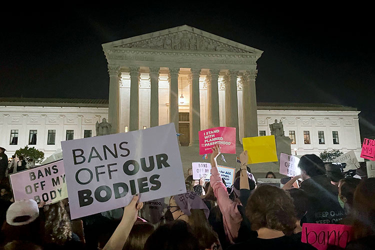 Pro-choice protesters hold signs outside the US Supreme Court building in Washington, D.C., the night the draft decision to overturn abortion rights was released