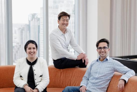 three people sitting on an orange couch