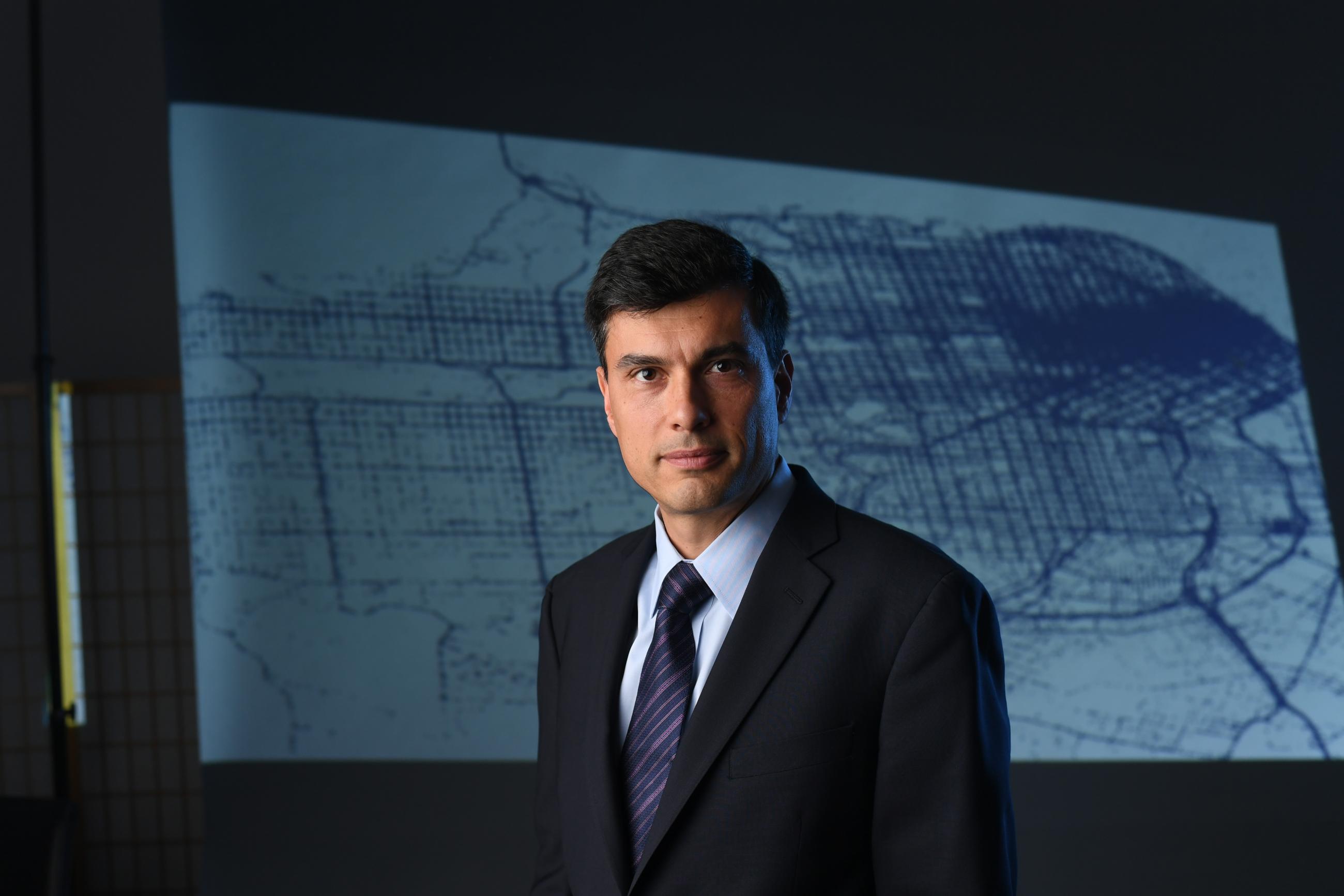 headshot of man in front of a poster